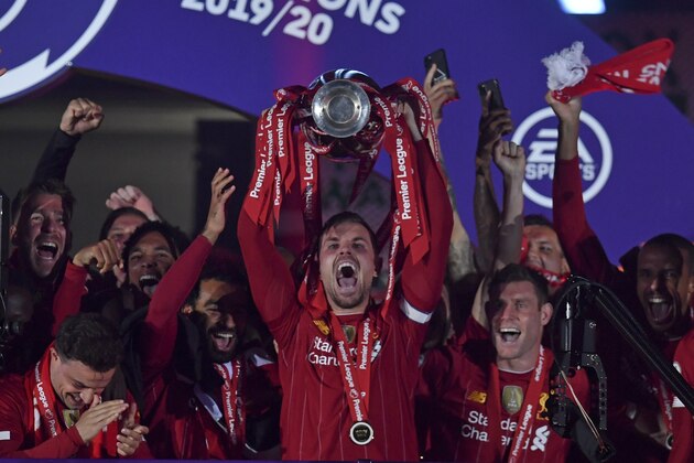 Liverpool's Jordan Henderson holds the English Premier League trophy aloft after it was presented following the Premier League soccer match between Liverpool and Chelsea at Anfield stadium in Liverpool, England, Wednesday, July 22, 2020. (Paul Ellis, Pool via AP)