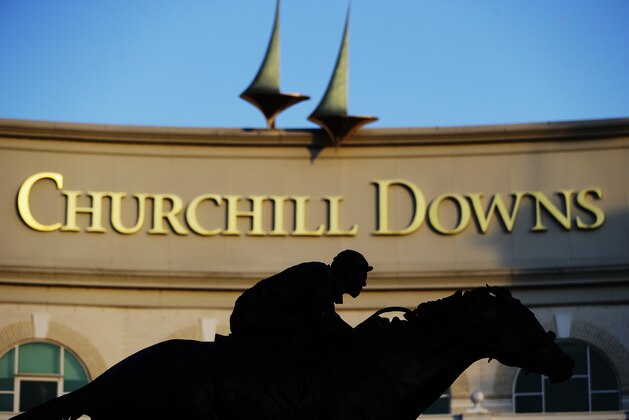 FILE - In this May 6, 2020 file photo a statue of Barbaro is silhouetted at the entrance of Churchill Downs in Louisville, Ky. Horse racing is in a state of transition at a time usually reserved for Triple Crown season. The Preakness would have been run Saturday, May 16, 2020 in Baltimore. But Pimlico Race Course and many tracks across North America remain dark because of the coronavirus pandemic. There is some light at the end of the tunnel as tracks including Churchill Downs in Kentucky are getting back to live racing without fans.  (AP Photo/Darron Cummings, file)