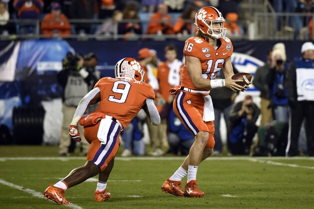 Clemson quarterback Trevor Lawrence (16) looks to hand off to Clemson running back Travis Etienne (9) during the first half of the Atlantic Coast Conference championship NCAA college football game against Virginia in Charlotte, N.C., Saturday, Dec. 7, 2019. (AP Photo/Mike McCarn)
