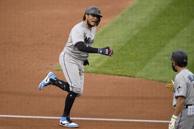 Miami Marlins' Miguel Rojas, left, reacts after rounding third base on his three-run home run during the second inning of a baseball game against the Washington Nationals, Friday, Aug. 21, 2020, in Washington. Marlins third base coach Trey Hillman, right, looks on. (AP Photo/Nick Wass)
