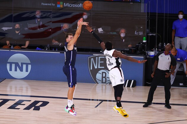 Dallas Mavericks' Luka Doncic, left, hits a winning three-point basket against Los Angeles Clippers' Reggie Jackson (1) during overtime of Game 4 of an NBA basketball first-round playoff series, Sunday, Aug. 23, 2020, in Lake Buena Vista, Fla. (Kevin C. Cox/Pool Photo via AP)