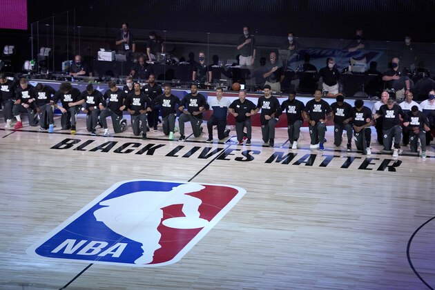 Members of the Milwaukee Bucks and the Boston Celtics kneel around a Black Lives Matter logo before the start of an NBA basketball game Friday, July 31, 2020, in Lake Buena Vista, Fla. (AP Photo/Ashley Landis, Pool)