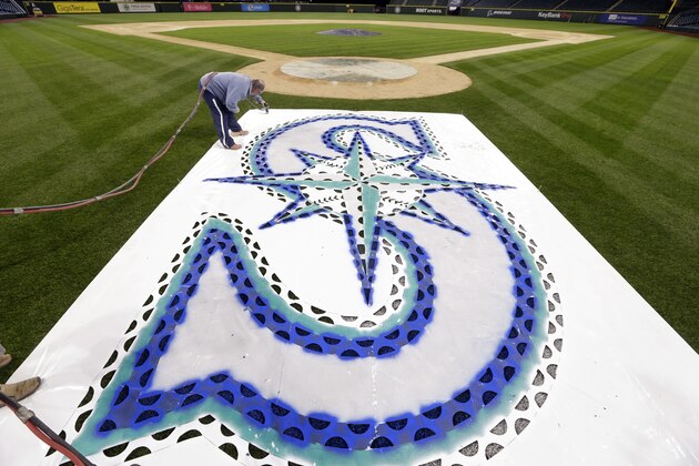 Seattle Mariners' head groundskeeper Bob Christofferson paints on a team logo stencil behind home plate in preparation for the new season Wednesday, April 1, 2015, in Seattle. The Mariners open at home against the Los Angeles Angles Monday, April 6. (AP Photo/Elaine Thompson)