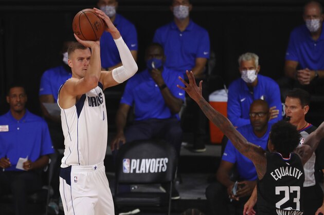 Dallas Mavericks forward Kristaps Porzingis shoots a 3-pointer against Los Angeles Clippers guard Lou Williams (23) during the first half of Game 1 of an NBA basketball first-round playoff series, Monday, Aug. 17, 2020, in Lake Buena Vista, Fla. (Kim Klement/Pool Photo via AP)