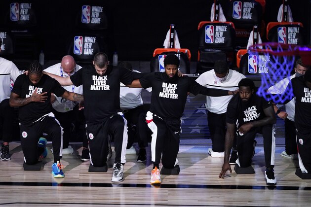 Los Angeles Clippers players kneel in honor of the Black Lives Matter movement during the playing of the national anthem prior to an NBA basketball game against the Dallas Mavericks Thursday, Aug. 6, 2020 in Lake Buena Vista, Fla. (AP Photo/Ashley Landis, Pool)