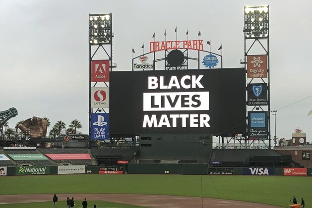 Groundskeepers work on the field as the scoreboard at Oracle Park reads Black Lives Matter at scheduled game time after a baseball game between the Los Angeles Dodgers and the San Francisco Giants was postponed on Wednesday, Aug. 26, 2020, in San Francisco. (AP Photo/Ben Margot)