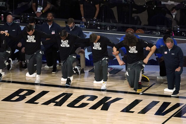 Members of the Milwaukee Bucks join arms as they kneel during the national anthem before an NBA basketball first round playoff game against the Orlando Magic Saturday, Aug. 29, 2020, in Lake Buena Vista, Fla. (AP Photo/Ashley Landis) Members of the Milwaukee Bucks join arms as they kneel during the national anthem before an NBA basketball first round playoff game against the Orlando Magic Saturday, Aug. 29, 2020, in Lake Buena Vista, Fla. (AP Photo/Ashley Landis)