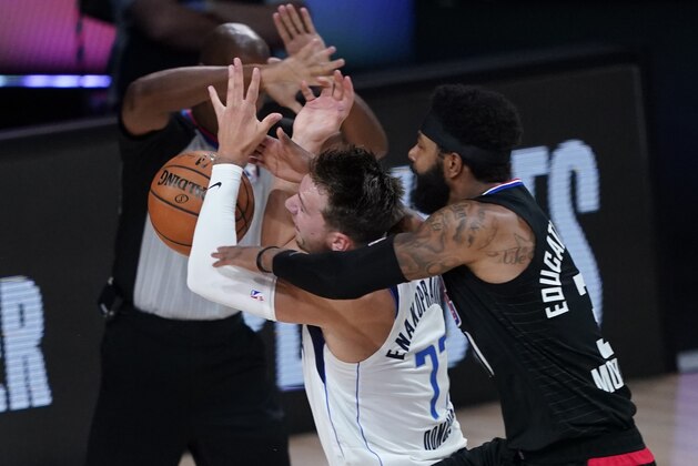 Dallas Mavericks' Luka Doncic (77) is fouled by Los Angeles Clippers' Marcus Morris Sr. during the first half of an NBA first round playoff game Sunday, Aug. 30, 2020, in Lake Buena Vista, Fla. (AP Photo/Ashley Landis)