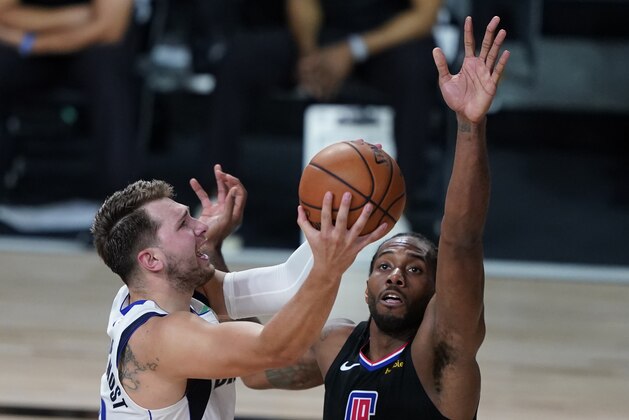Los Angeles Clippers' Kawhi Leonard (2) fouls Dallas Mavericks' Luka Doncic (77) during the second half of an NBA first round playoff game Sunday, Aug. 30, 2020, in Lake Buena Vista, Fla. (AP Photo/Ashley Landis)