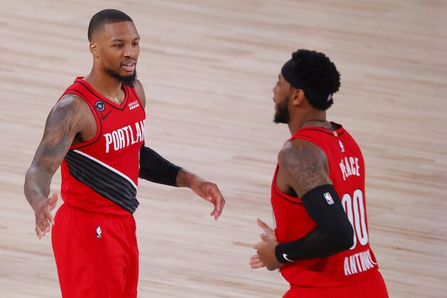 Portland Trail Blazers' Damian Lillard, left, and teammate Carmelo Anthony (00) react during the second quarter of Game 2 of an NBA basketball first-round playoff series against the Los Angeles Lakers, Thursday, Aug. 20, 2020, in Lake Buena Vista, Fla. (Kevin C. Cox/Pool Photo via AP)