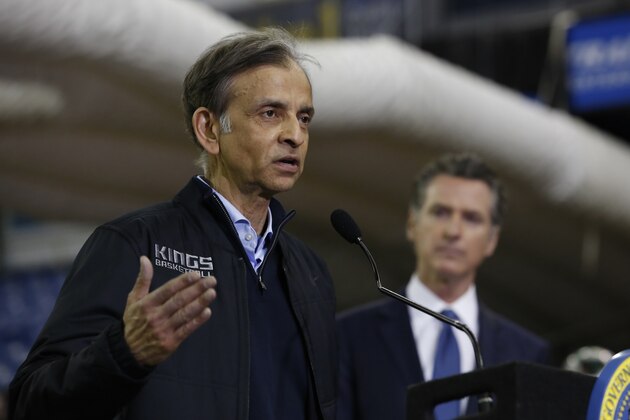Vivek Ranadive, left, the owner of the NBA's Sacramento Kings basketball team, flanked by Gov. Gavin Newsom, right, discusses the donation of Sleep Train Arena, the team's former home, for use as a field hospital, after touring the facility in Sacramento, Calif., Monday, April 6, 2020. The arena is being transformed for use as a 400-bed emergency field hospital to help deal with the coronavirus outbreak. (AP Photo/Rich Pedroncelli, Pool)