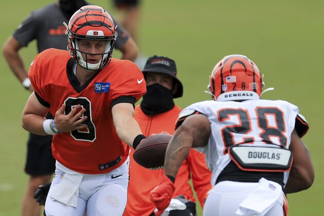 Cincinnati Bengals' Joe Burrow (9) hands the ball off to Joe Mixon (28) during an NFL football camp practice in Cincinnati, Tuesday, Aug. 18, 2020. (AP Photo/Aaron Doster)