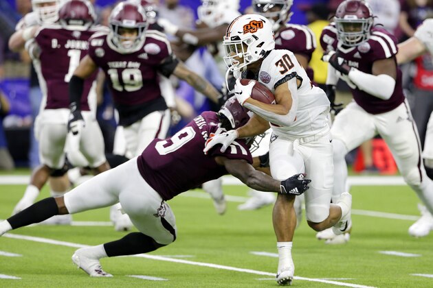 Oklahoma State running back Chuba Hubbard (30) is caught by Texas A&M defensive back Leon O'Neal Jr. (9) during the first half of the Texas Bowl NCAA college football game Friday, Dec. 27, 2019, in Houston. (AP Photo/Michael Wyke)