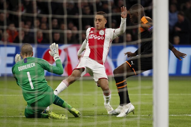 Valencia's goalkeeper Jaume Domenech saves on a shot by Ajax's Sergino Dest, center, during the group H Champions League soccer match between Ajax and Valencia at the Johan Cruyff ArenA in Amsterdam, Netherlands, Tuesday, Dec. 10, 2019. (AP Photo/Peter Dejong)