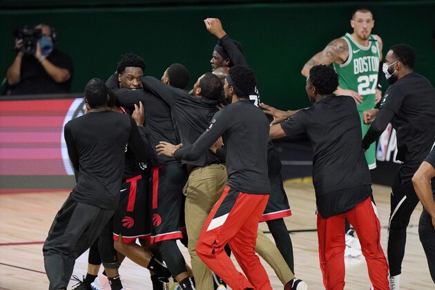 Teammates mob Toronto Raptors' OG Anunoby, second player from left, after Anunoby's game winning shot at the buzzer in the second half of an NBA conference semifinal playoff basketball game against the Boston Celtics Thursday, Sept 3, 2020, in Lake Buena Vista Fla. Celtic's Daniel Theis is at rear. (AP Photo/Mark J. Terrill)