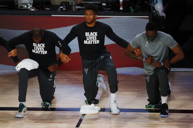 Milwaukee Bucks' Giannis Antetokounmpo, second from right, takes a knee during the national anthem before an NBA basketball game between the Dallas Mavericks and the Bucks on Saturday, Aug. 8, 2020, in Lake Buena Vista, Fla. (Kevin C. Cox/Pool Photo via AP)