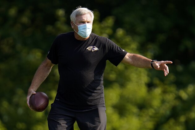 Baltimore Ravens offensive line coach Joe D'Alessandris wears a face mask to protect against COVID-19 as he instructs his players how to run a drill during an NFL football training camp practice, Tuesday, Aug. 25, 2020, in Owings Mills, Md. (AP Photo/Julio Cortez)