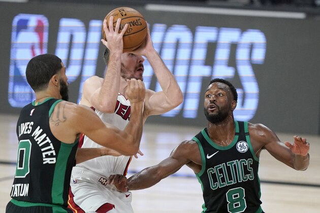 Boston Celtics' Jayson Tatum (0) and Kemba Walker, right, defend as Miami Heat's Goran Dragic, center, drives to the basket for a shot during the first half of an NBA conference final playoff basketball game, Tuesday, Sept. 15, 2020, in Lake Buena Vista, Fla. (AP Photo/Mark J. Terrill)