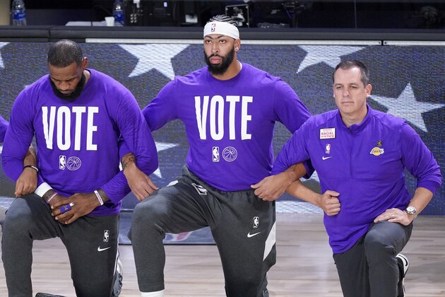 Los Angeles Lakers' LeBron James, from left, Anthony Davis and head coach Frank Vogel, right, lock arms during the playing of the national anthem before an NBA conference final playoff basketball game against the Denver Nuggets on Friday, Sept. 18, 2020, in Lake Buena Vista, Fla. (AP Photo/Mark J. Terrill) Los Angeles Lakers' LeBron James, from left, Anthony Davis and head coach Frank Vogel, right, lock arms during the playing of the national anthem before an NBA conference final playoff basketball game against the Denver Nuggets on Friday, Sept. 18, 2020, in Lake Buena Vista, Fla. (AP Photo/Mark J. Terrill)