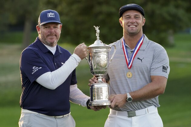 Bryson DeChambeau, of the United States, right, holds up the winner's trophy with his caddie, Tim Tucker, after winning the US Open Golf Championship, Sunday, Sept. 20, 2020, in Mamaroneck, N.Y. (AP Photo/John Minchillo)
