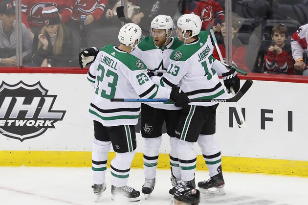 Dallas Stars defenseman Esa Lindell (23) and center Mattias Janmark (13) celebrate with center Joe Pavelski, center, after Pavelski's winning goal in overtime of an NHL hockey game Saturday, Feb. 1, 2020, in Newark, N.J. (AP Photo/Noah K. Murray)
