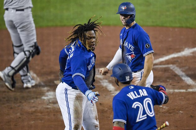 Toronto Blue Jays' Vladimir Guerrero Jr., left, and Randal Grichuk, top, celebrate with Jonathan Villar after Guerrero and Grichuk scored against the New York Yankees on a double by Alejandro Kirk during the sixth inning of a baseball game in Buffalo, N.Y., Thursday, Sept. 24, 2020. (AP Photo/Adrian Kraus)
