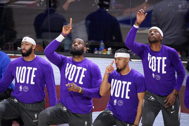 Los Angeles Lakers' Anthony Davis, left, LeBron James, Quinn Cook and Kentavious Caldwell-Pope, right, participate in the playing of the national anthem during the first half of an NBA conference final playoff basketball game against the Denver Nuggets on Tuesday, Sept. 22, 2020, in Lake Buena Vista, Fla. (AP Photo/Mark J. Terrill)