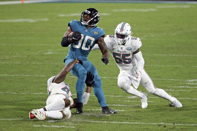 Jacksonville Jaguars running back James Robinson, center, looks for a way to get past Miami Dolphins outside linebacker Elandon Roberts, left, and outside linebacker Jerome Baker (55) during the second half of an NFL football game, Thursday, Sept. 24, 2020, in Jacksonville, Fla. (AP Photo/Stephen B. Morton)