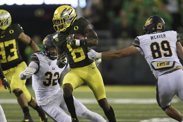 Oregon's Jevon Holland runs between California's Daniel Scott, left, and Evan Weaver, right, during the third quarter of an NCAA college football game Saturday, Oct. 5, 2019, in Eugene, Ore. (AP Photo/Chris Pietsch)