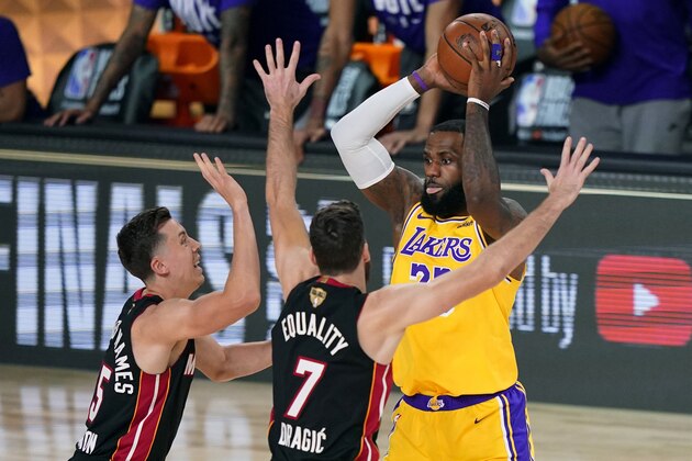 Los Angeles Lakers' LeBron James, right, looks to pass while covered by Miami Heat's Duncan Robinson, left, and Goran Dragic (7) during the first half of Game 1 of basketball's NBA Finals Wednesday, Sept. 30, 2020, in Lake Buena Vista, Fla. (AP Photo/Mark J. Terrill)