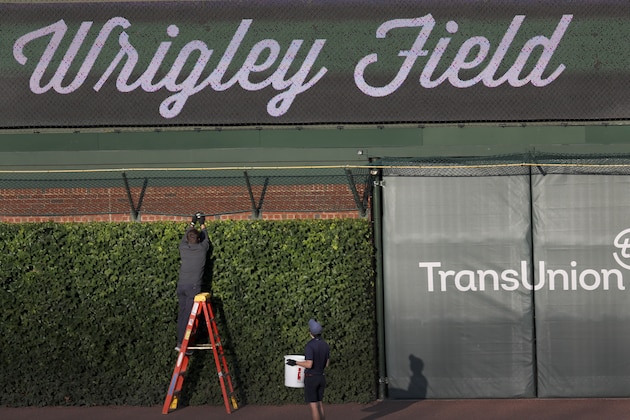 A Chicago Cubs employee retrieves a baseball from the right field basket after batting practice and before a baseball game between the Chicago Cubs and the Kansas City Royals Tuesday, Aug. 4, 2020, in Chicago. (AP Photo/Charles Rex Arbogast)