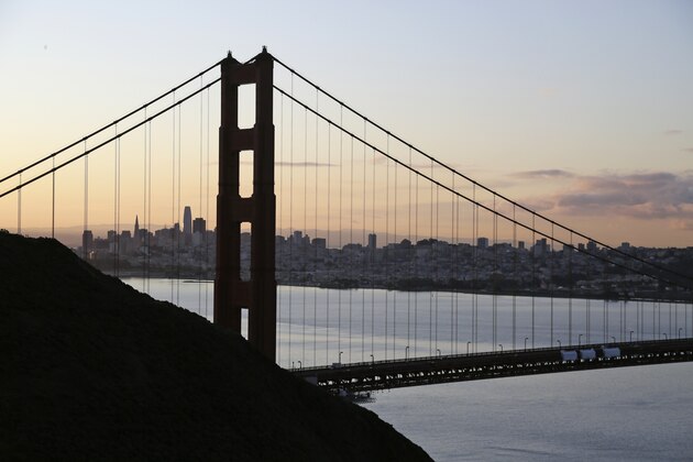 The San Francisco skyline is seen shortly after sunrise behind the Golden Gate Bridge Tuesday, March 17, 2020, in Sausalito, Calif. About 7 million people in the San Francisco Bay Area woke up Tuesday to nearly empty highways, shuttered stores and vacant streets after officials issued an order for residents to shelter at their homes and only leave for