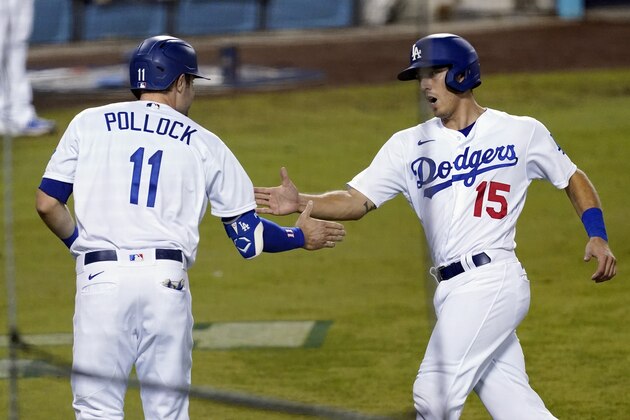 Los Angeles Dodgers' A.J. Pollock (11) and Austin Barnes (15) shake hands after they scored on a a double by Mookie Betts during the fifth inning in Game 2 of the team's National League wild-card baseball series against the Milwaukee Brewers on Thursday, Oct. 1, 2020, in Los Angeles. (AP Photo/Ashley Landis)