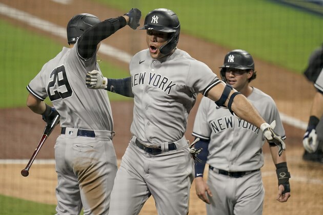 New York Yankees designated hitter Giancarlo Stanton, center, celebrates with teammates after hitting a grand slam home run against the Tampa Bay Rays during the ninth inning in Game one of a baseball American League Division Series Monday, Oct. 5, 2020, in San Diego. (AP Photo/Jae C. Hong)