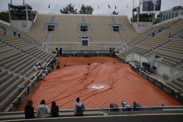 Stadium workers cover Suzanne Lenglen court as rain delayed a fourth round match of the French Open tennis tournament at the Roland Garros stadium in Paris, France, Monday, Oct. 5, 2020. (AP Photo/Alessandra Tarantino)