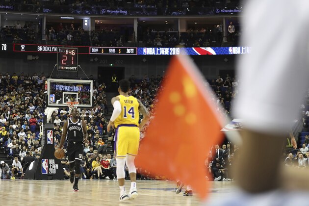 In this Thursday, Oct. 10, 2019, photo, Brooklyn Nets' Theo Pinson, left, drives against Los Angeles Lakers' Danny Green, right, near a Chinese national flag during a preseason NBA game at the Mercedes Benz Arena in Shanghai, China. When Houston Rocket's general manager Daryl Morey tweeted last week in support of anti-government protests in Hong Kong, everything changed for NBA fans in China. A new chant flooded Chinese sports forums:
