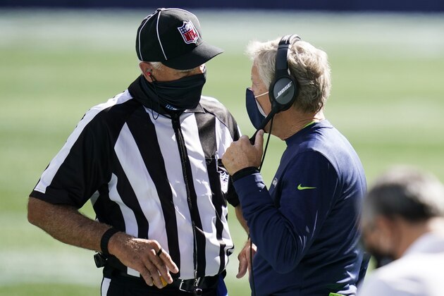 Seattle Seahawks head coach Pete Carroll wears a mask as he talks to an official during the first half of an NFL football game against the Dallas Cowboys, Sunday, Sept. 27, 2020, in Seattle. (AP Photo/Elaine Thompson)
