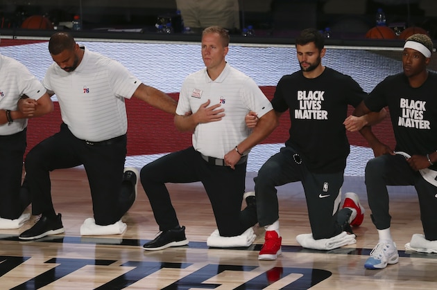 Philadelphia 76ers head coach Brett Brown, left, and team members kneel during the national anthem before an NBA basketball game against the Houston Rockets, Friday, Aug. 14, 2020, in Lake Buena Vista, Fla. (Kim Klement/Pool Photo via AP) Philadelphia 76ers head coach Brett Brown, left, and team members kneel during the national anthem before an NBA basketball game against the Houston Rockets, Friday, Aug. 14, 2020, in Lake Buena Vista, Fla. (Kim Klement/Pool Photo via AP)