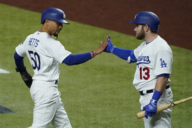 Los Angeles Dodgers' Max Muncy (13) celebrates after Mookie Betts (50) scored off a single by Justin Turner against the San Diego Padres during the sixth inning in Game 1 of a baseball NL Division Series, Tuesday, Oct. 6, 2020, in Arlington, Texas. (AP Photo/Tony Gutierrez)