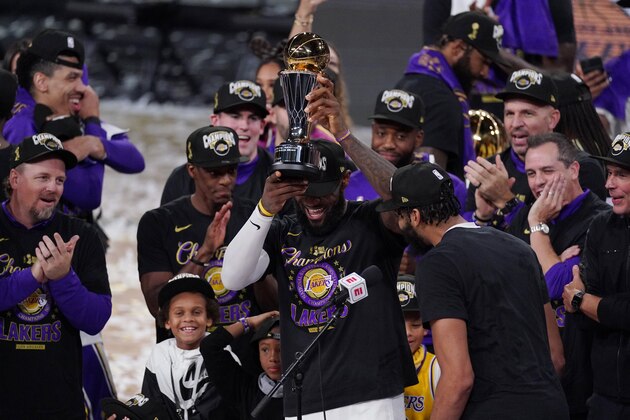 Los Angeles Lakers' LeBron James (23) holds the MVP trophy as he celebrates with his teammates after the Lakers defeated the Miami Heat 106-93 in Game 6 of basketball's NBA Finals Sunday, Oct. 11, 2020, in Lake Buena Vista, Fla. (AP Photo/Mark J. Terrill)