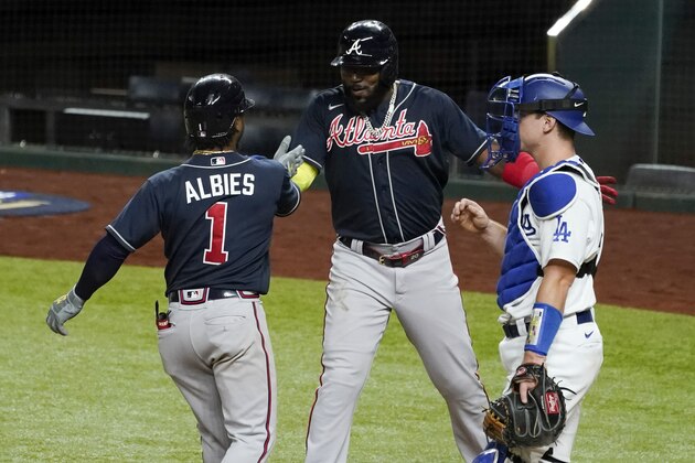 Atlanta Braves' Ozzie Albies celebrates his two-run home run with Marcell Ozuna against the Los Angeles Dodgers during the ninth inning in Game 1 of a baseball National League Championship Series Monday, Oct. 12, 2020, in Arlington, Texas. (AP Photo/Tony Gutierrez)