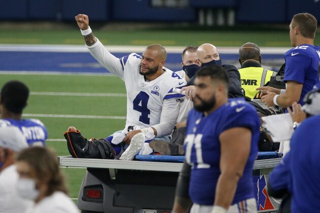 Dallas Cowboys quarterback Dak Prescott (4) lifts his fist to cheers from fans as he is carted off the field after suffering a lower right leg injury running the ball in the second half of an NFL football game against the New York Giants in Arlington, Texas, Sunday, Oct. 11, 2020. (AP Photo/Michael Ainsworth)