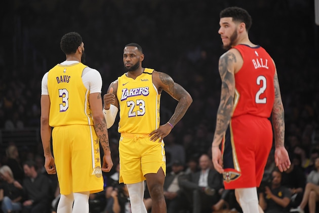 Los Angeles Lakers forward Anthony Davis, left, talks with forward LeBron James, center, as New Orleans Pelicans guard Lonzo Ball walks nearby during the first half of an NBA basketball game Friday, Jan. 3, 2020, in Los Angeles. (AP Photo/Mark J. Terrill)