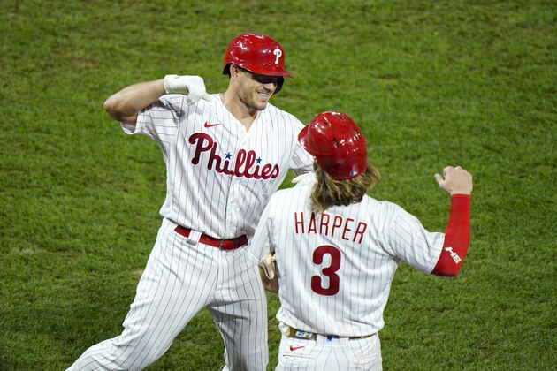 Philadelphia Phillies' J.T. Realmuto, left, and Bryce Harper celebrate after Realmuto's three-run home run off New York Mets pitcher Walker Lockett during the fifth inning of a baseball game, Friday, Aug. 14, 2020, in Philadelphia. (AP Photo/Matt Slocum)