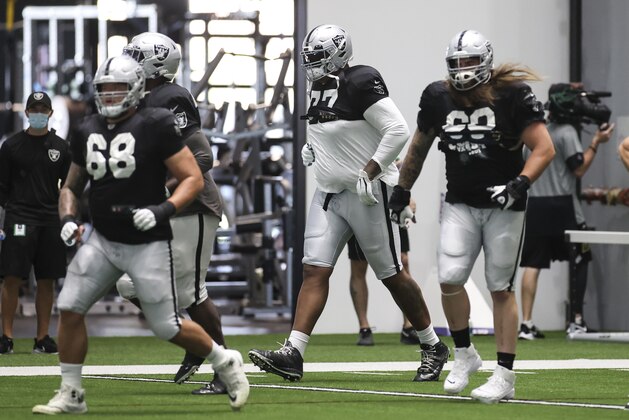 Las Vegas Raiders offensive tackle Trent Brown, center, warms up alongside offensive tackle Andre James (68) and guard Jordan Roos during an NFL football training camp practice Wednesday, Aug. 26, 2020, in Henderson, Nev. (Chase Stevens/Las Vegas Review-Journal via AP, Pool)