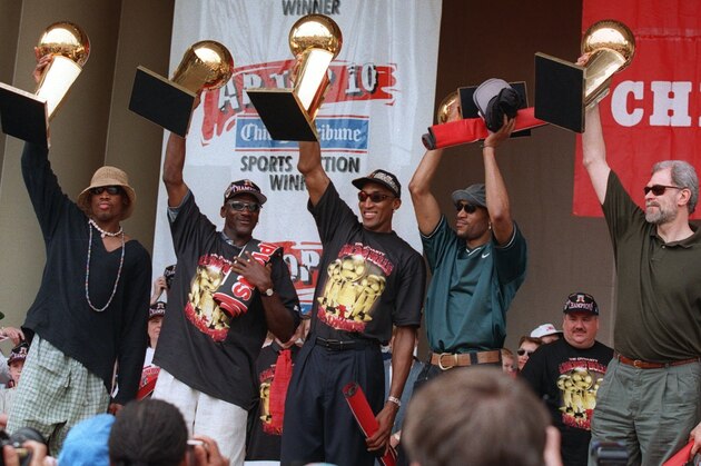 The Chicago Bulls' Dennis Rodman, left, Michael Jordan, Scottie Pippen, Ron Harper and coach Phil Jackson, right, hoist the team's five NBA Championship trophies aloft during a celebration in Chicago's Grant Park on Monday, June 16, 1997.  The Bulls beat the Utah Jazz 4-2 in the best-of-7 NBA Finals. (AP Photo/Michael Conroy)