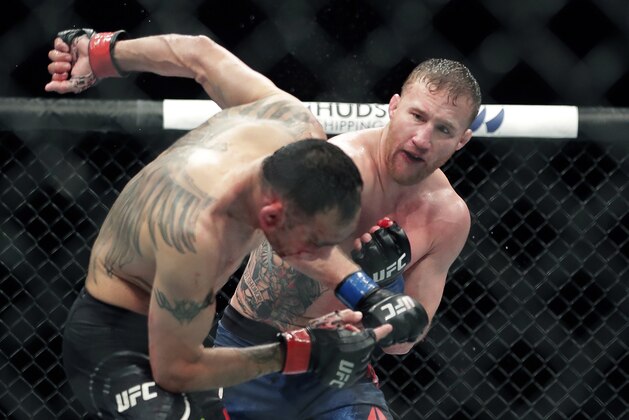 Tony Ferguson, left, falls backward after taking a punch from Justin Gaethje during a UFC 249 mixed martial arts bout, early Sunday, May 10, 2020, in Jacksonville, Fla. (AP Photo/John Raoux)