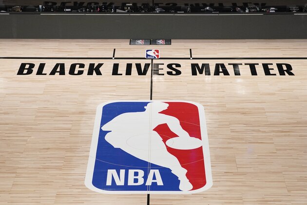 Black Lives Matter is displayed near the NBA logo in an empty basketball arena Friday, Aug. 28, 2020, in Lake Buena Vista, Fla.  The NBA playoffs will resume Saturday after the league and the National Basketball Players Association detailed the commitments that made players comfortable continuing the postseason. (AP Photo/Ashley Landis, Pool)
