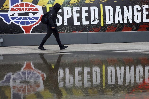A pit crew member walks past the media center as crews wait out a delay at a NASCAR Cup Series auto race after morning rain prevented the 9 a.m. rescheduled start at Texas Motor Speedway in Fort Worth, Texas, Monday, Oct. 26, 2020. (AP Photo/Richard W. Rodriguez)