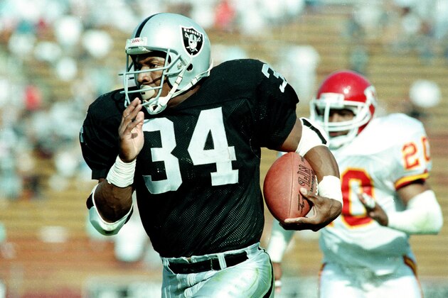 Bo Jackson, the two-sport star and running back for the Los Angeles Raiders, takes off on a 45-yard run against the Kansas City Chiefs, including free safety Deron Cherry (20), early in the fourth quarter of Sunday, October 15, 1989 game at the Coliseum in Los Angeles. (AP Photo/Bob Galbraith)
